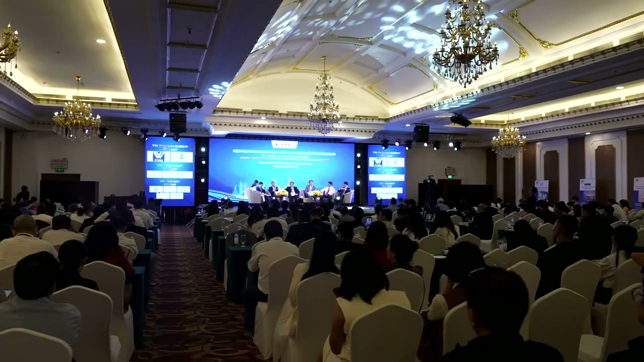 The Mira Hotel ballroom filled with VATIC 2026 attendees beneath its chandeliers, with the conference stage at the front.
